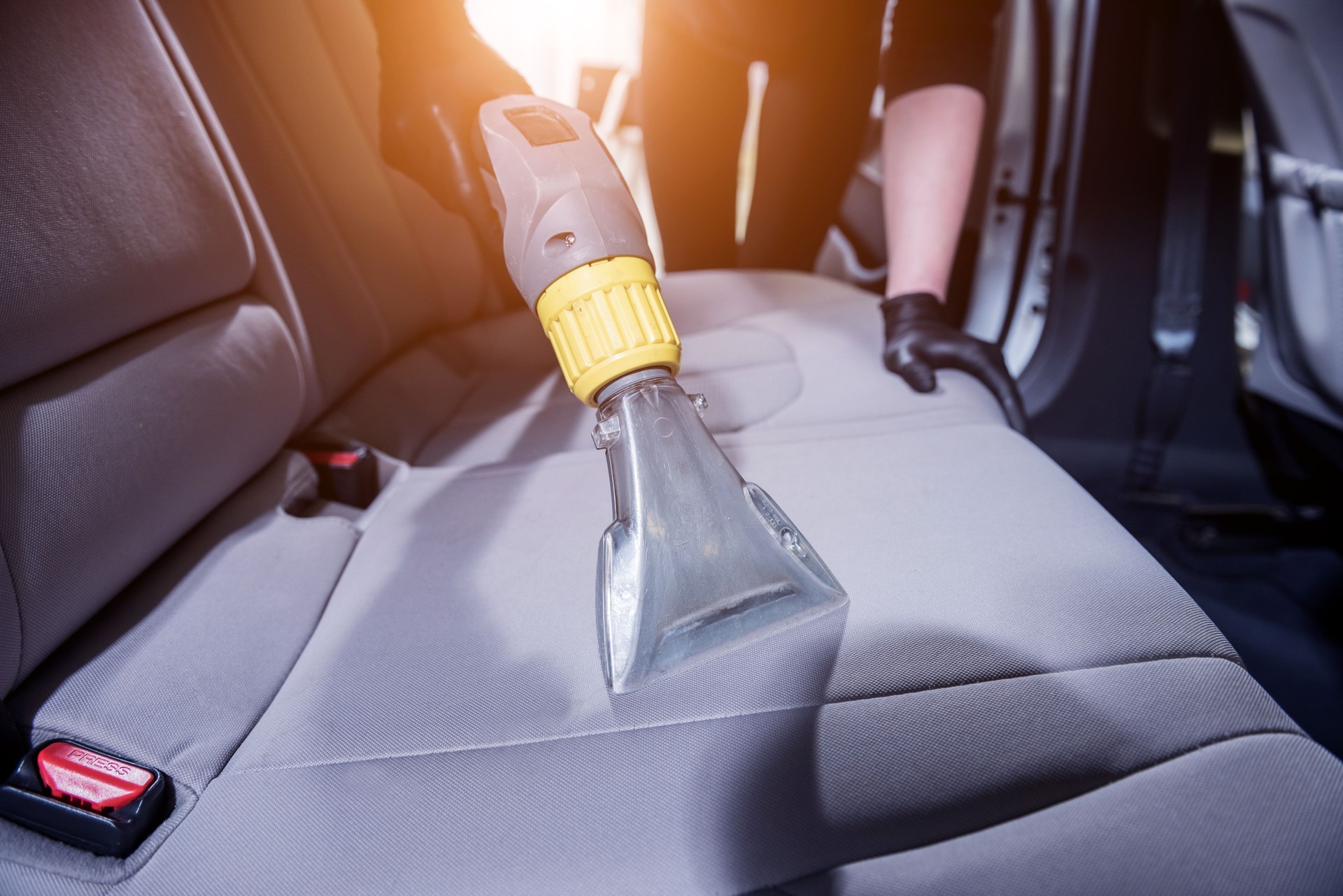 Arbeiter reinigt Autoinnenraum mit Staubsauger