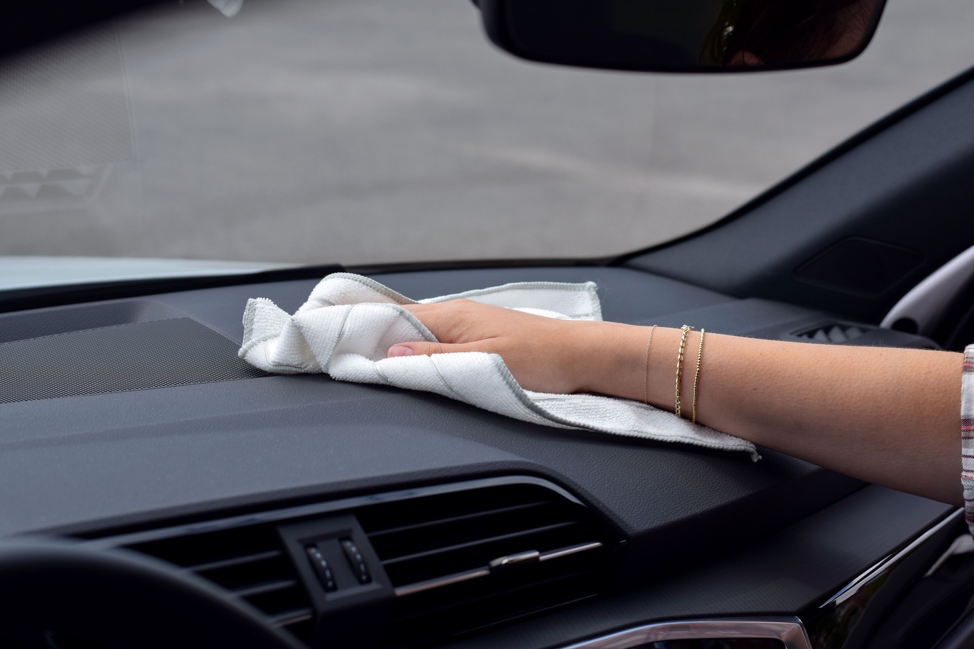 Hand einer Frau, die das Armaturenbrett des Autos reinigt